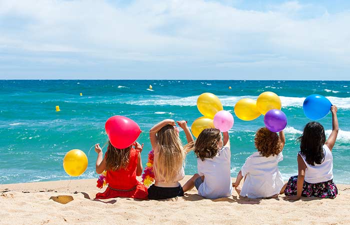 Niños con globos de colores disfrutando de la fiesta de cumpleaños en la playa