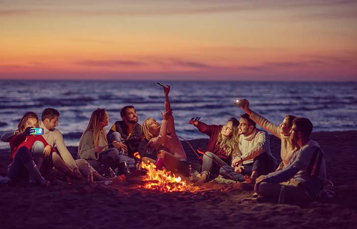 un grupo de amigos disfrutando de una fiesta con hogueras en la playa